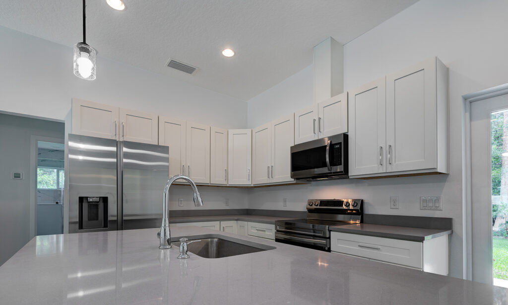 kit home kitchen with white cabinets, grey granite top kitchen island and stainless steel appliances