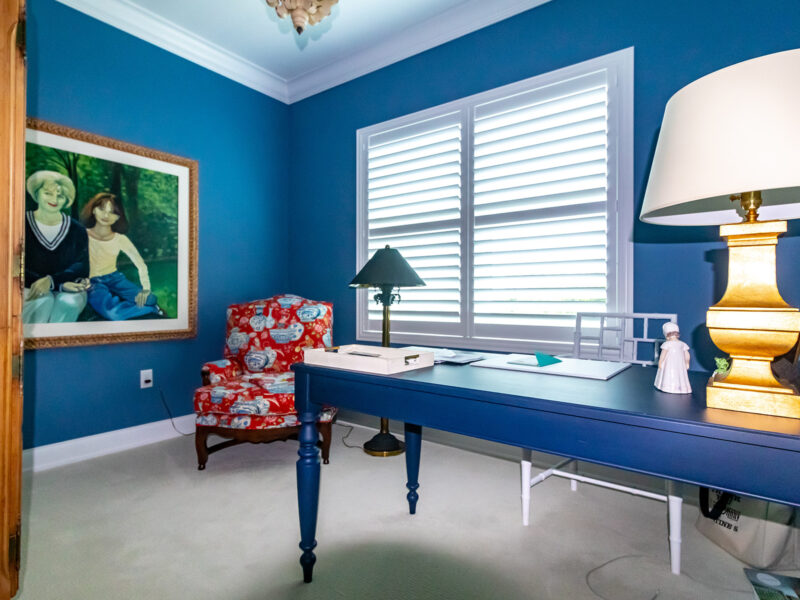 home office with deep blue walls, beige carpet, white crown moulding, and a large painting on the wall
